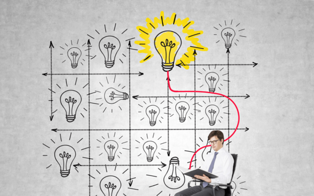 Man sitting on a chair, surrounded by grey light bulbs and one bright one