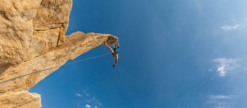 A climber hangs off the very edge of a protruding rock.